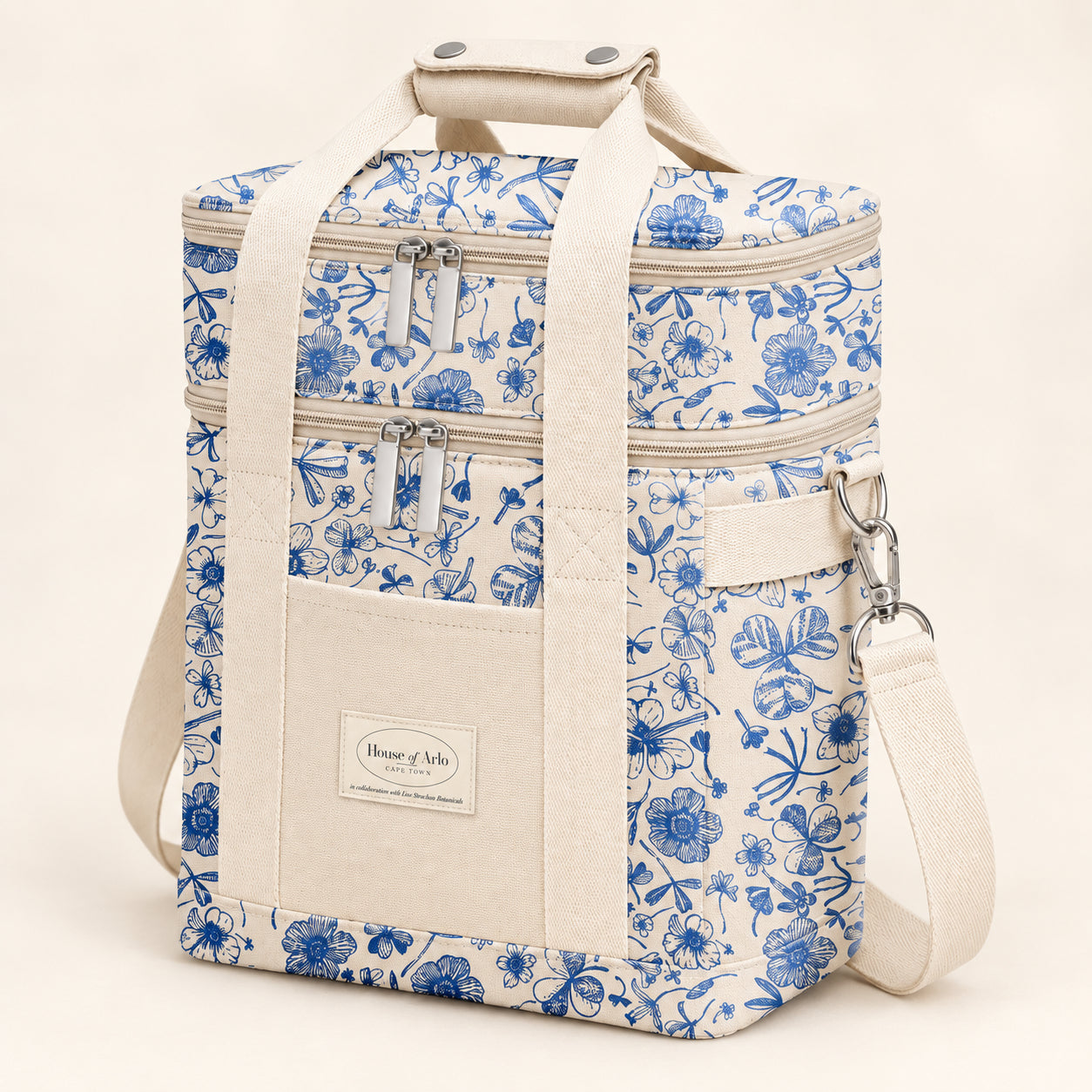 Product mockup of the blue botanical picnic bag with two zip compartments, cream handles and front pocket